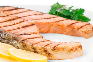 Grilled salmon steak with vegetables on plate.