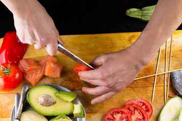 chef slicing tomato on a wooden board