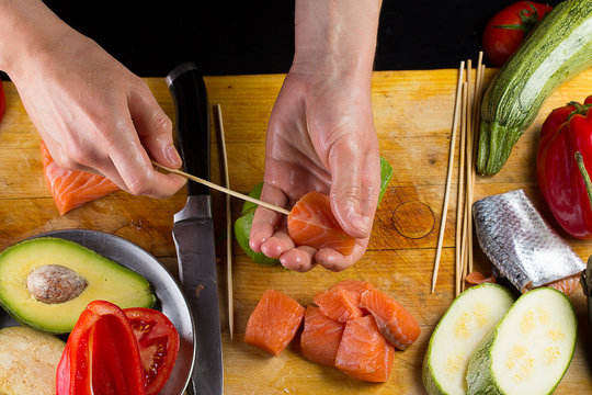 Chef is implating salmon filett on a skewer