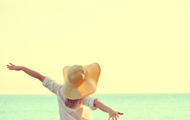 Happy woman in hat is back  opened his hands, enjoys sunset