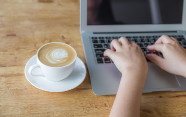 Closeup of business woman hand typing on laptop keyboard and cof