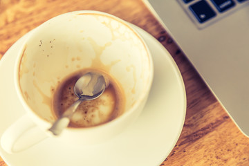 Empty coffee cup and laptop on old wooden table ( Filtered image