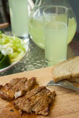 Pork steak in front of glass and jar with cucumber lemonade