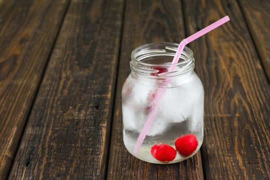 Two cherries in cold drink in a jar with pink straw