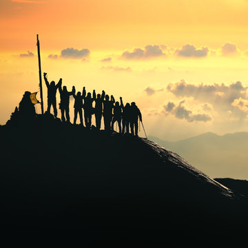 Teamwork. A group of people are standing on the top of the mountain. 