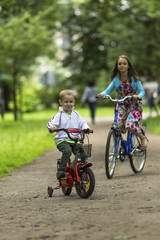 Little boy with his sister ride bikes in the Park.