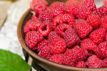 fresh ripe raspberries in clay plate