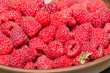 fresh ripe raspberries in clay plate