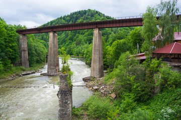 Fototapeta na wymiar Railway and an old suspension bridge across mountain river
