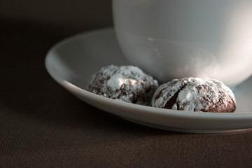 Cracked chocolate cookies with icing sugar and a cup of coffee