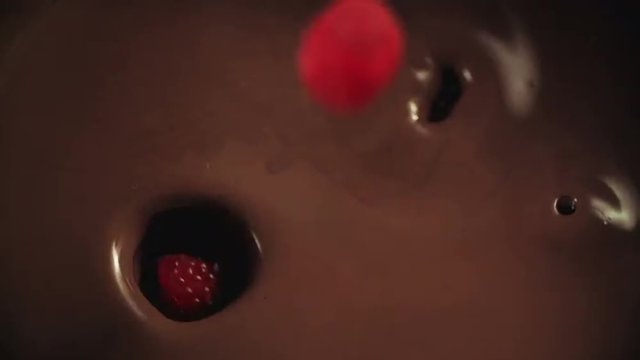 Raspberries falling into melted chocolate. Shoot on Digital Cinema Camera in slow motion - ProRes 422 codec.