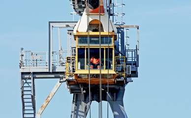 Dockside crane with worker pilot in the cabin.