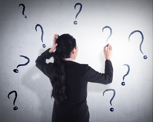 Business woman write question mark on the wall