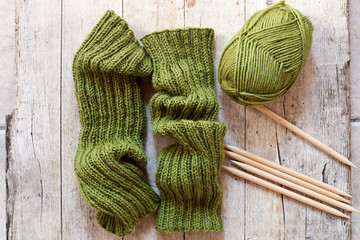 wool green legwarmers, knitting needles and yarn