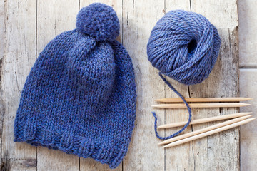 wool blue hat, knitting needles and yarn