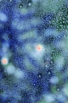 Raindrops on glass, natural blue  background, selective focus