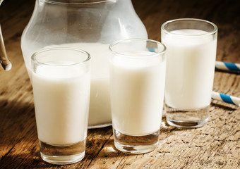 Fresh peasant milk jug and glasses on old wooden table, selectiv