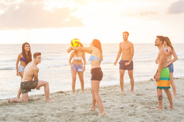 Group of friends playing with ball on the beach