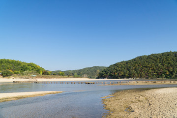 single lane log bridge over a shallow river