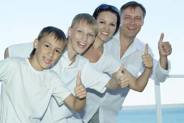 Happy family of four showing thumbs up