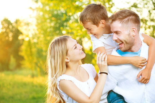 Happy Joyful Young Family Having Fun Outdoors In Summer Park