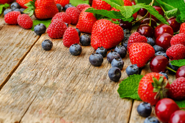 wood background with fresh berries, strawberries, blueberries, c
