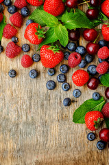 wood background with fresh berries, strawberries, blueberries, c