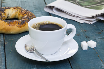 Cup of coffee with bagel and newspaper
