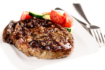 Grilled steak and vegetables on white plate with fork