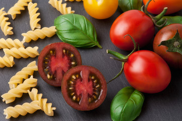 Pasta ingredients concept on black slate background viewed from the top