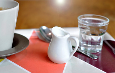 Cup of coffee and glass of water on table in a cafe.