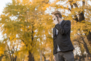 Young man with mobile phone in the autumn park