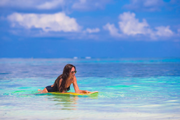 Young slender surf girl at white beach with yellow surfboard