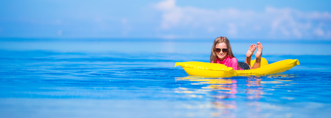 Adorable girl with inflatable air mattress in outdoor swimming