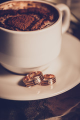 Cup of coffee, wedding rings and wedding bouquet of tulips
