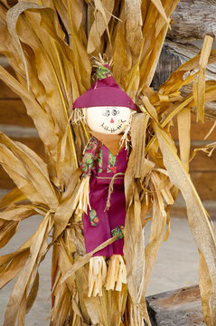 Small Scarecrow Sits In The Middle Of A Corn Stack.