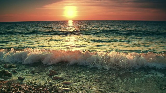 Slow motion. Sea waves near the shore on sunset or sunrise. Beautiful golden hour sea surf landscape. Calm and relax background.