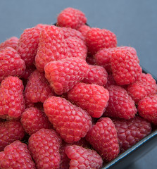 Fresh raspberries in a black bowl, on a black background
