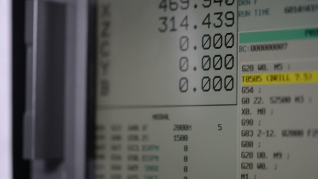 CNC machine monitor display with program code running and numbers with parameters changing