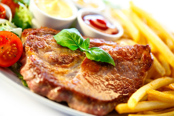 Grilled steak, French fries and vegetables on white background