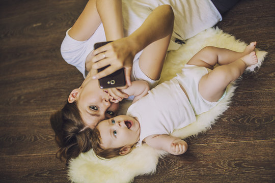 Woman with a baby doing a selfie lying on floor