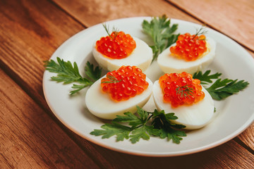 Boiled eggs with red salmon caviar
