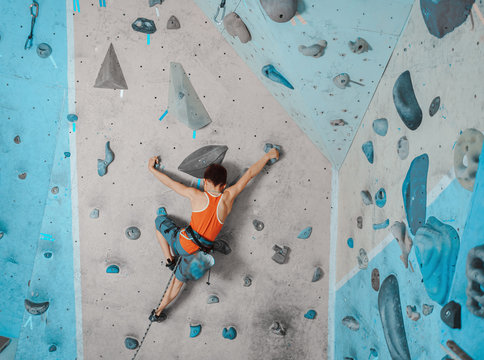 Boy in safety equipment climbing in gym