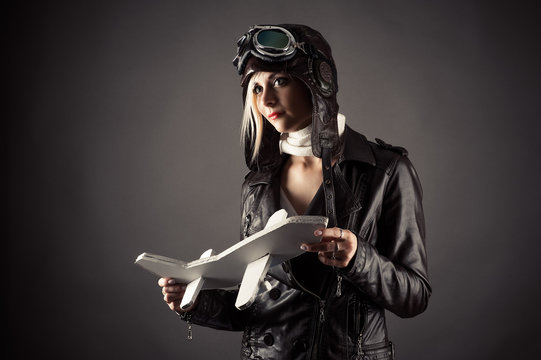 beautiful woman in aviator hat standing with toy airplane in hand