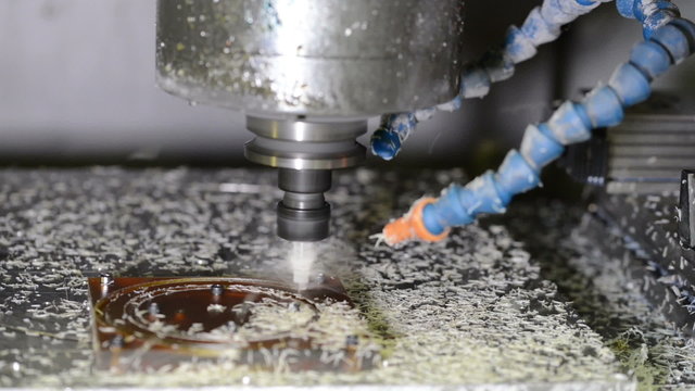 Working CNC milling machine drills in plastic detail making plastic shaving scrap 