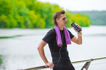 Young sports man with towel and bottle of water after jogging