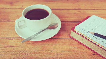 a cup of coffee and a target text on note book. process color.