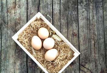 Eggs in basket on wooden background. Image filtered