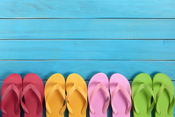 Flip flops or flipflop in a row line bottom border with old blue wood deck decking background...