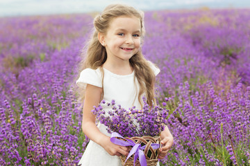 Pretty child girl in lavender field with basket of flowers